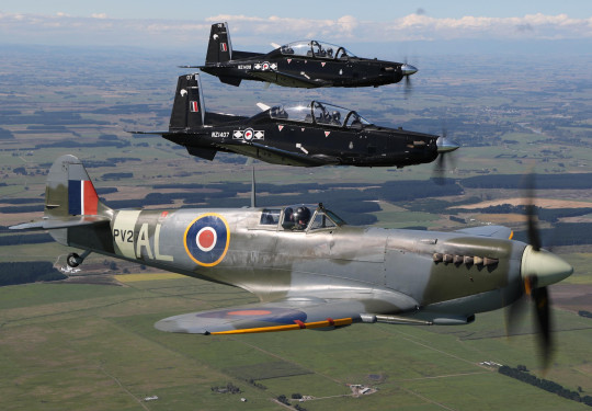 Supermarine Spitfire and two modern Beechcraft T-6C Texan II aircraft flying in formation