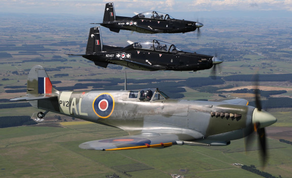 Supermarine Spitfire and two modern Beechcraft T-6C Texan II aircraft flying in formation