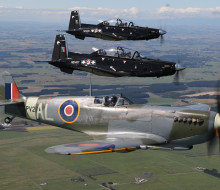 Supermarine Spitfire and two modern Beechcraft T-6C Texan II aircraft flying in formation