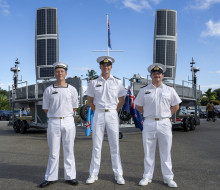 Three sailors stand in a row in uniform, hands behind their backs