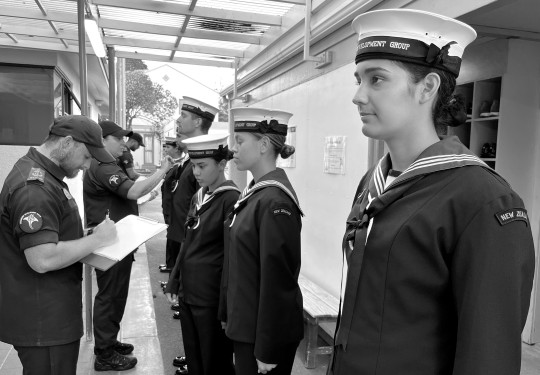 Navy recruits stand in a line as they have their uniform inspected during the Basic Common Training course.