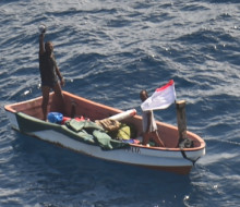 Two people on a small boat who went missing in Kiribati waters waving to camera (on aircraft) RNZAF P-3K2 Orion following a two-day search.
