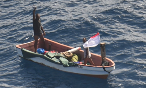 Two people on a small boat who went missing in Kiribati waters waving to camera (on aircraft) RNZAF P-3K2 Orion following a two-day search.