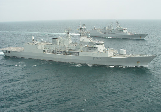 HMNZS Te Mana (background) joins HMNZS Te Kaha (foreground) at the end of the latter’s deployment.