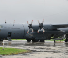 A Royal New Zealand Hercules aircraft on the tarmac at the airport in Tonga. Air Force personnel are removing supplies from the aircraft