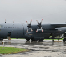 A Royal New Zealand Hercules aircraft on the tarmac at the airport in Tonga. Air Force personnel are removing supplies from the aircraft