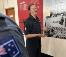 Woman smiles as she stands in front of a sign.