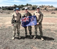 Three soldiers holding New Zealand flag