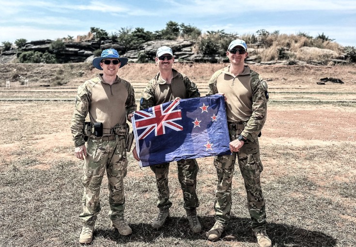 Three soldiers holding New Zealand flag
