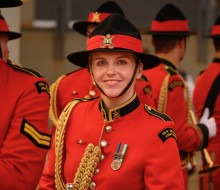 A NZ Army band member smiles to the camera while other members of the band are facing away in the background.