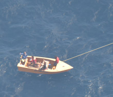An aerial photo of a small boat with off Kiribati with three men on board.