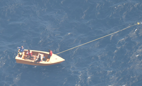 An aerial photo of a small boat with off Kiribati with three men on board.