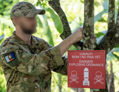 A member of the Kiwi team deployed to Operation Render Safe hangs up a warning sign.