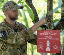 A member of the Kiwi team deployed to Operation Render Safe hangs up a warning sign.