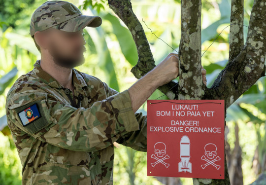 A member of the Kiwi team deployed to Operation Render Safe hangs up a warning sign.