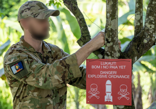 A member of the Kiwi team deployed to Operation Render Safe hangs up a warning sign.