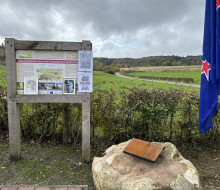Looking beyond the plaque towards the crash site - there is a New Zealand flag on the right. 
