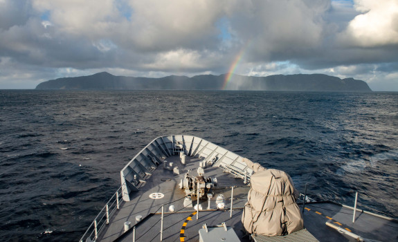 HMNZS Wellington with Raoul Island in the background, taken in August this year. The photo is taken from the bridge of the ship. Towards the island you can see a small rainbow. 