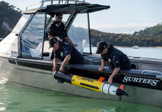 Navy personnel deploy a Remus Autonomous Underwater Vehicle over the side of a Pathfinder aluminium workboat.