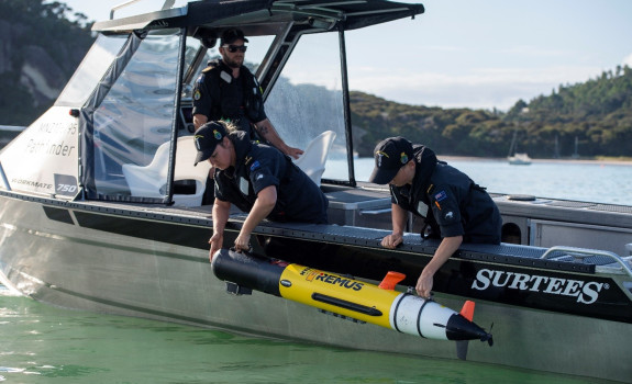 Navy personnel deploy a Remus Autonomous Underwater Vehicle over the side of a Pathfinder aluminium workboat.