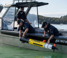 Navy personnel deploy a Remus Autonomous Underwater Vehicle over the side of a Pathfinder aluminium workboat.