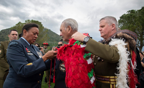 Chief of New Zealand Army Major General John Boswell (right) places our Ngā Tapuwae kahu huruhuru on the last surviving member of B Company, Robert Gillies 2019. A member of the RNZAF assists in the tie on a cloudy day.