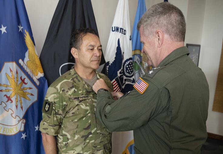 A man in military uniforn receives the Legion of Merit from an Admiral with a United States flag on their arm.