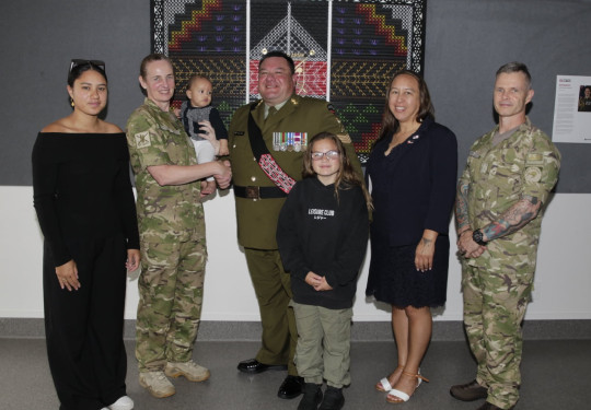 A group photo of three soldiers and two civilian adults, a child and a baby.