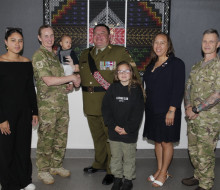 A group photo of three soldiers and two civilian adults, a child and a baby.