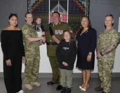 A group photo of three soldiers and two civilian adults, a child and a baby.