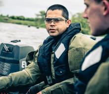 Soldier with lifejacket and protective glasses controls the small boat they are aboard.