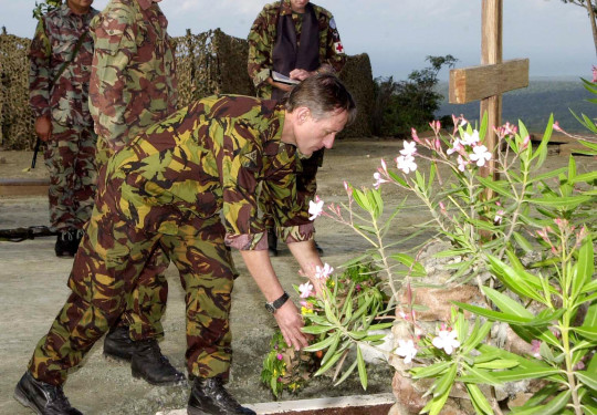 A man in camouflage uniform lays a wreath surrounded by plants in Timor-Leste.