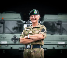 LTCOL Ropitini stands with arms crossed, wearing Army uniform in from of two MHOVs.