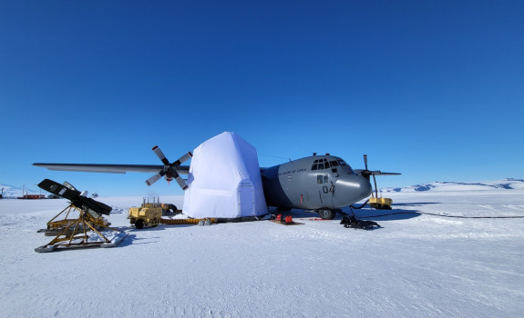 A grey aircraft on the ice in Antarctica. The aircraft has a white box around the right wing.