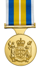 A gold coloured medal hung on a white, blue and yellow striped ribbon. The medal show the overs pattern which is the New Zealand Coat of Arms. The stripe pattern on the ribbon is horizontally symmetric. From the outside in there is a narrow white stripe, 