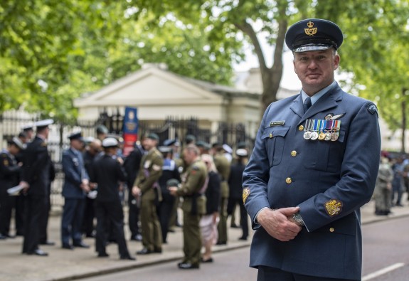Warrant Officer Paul Chadwick in Air Force uniform standing in front of the various contingents under the green trees of Summer.