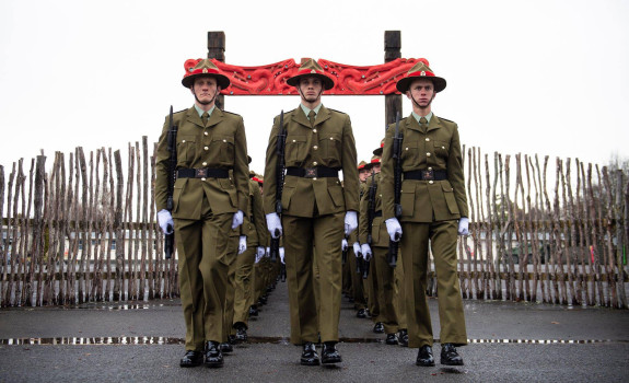 New Zealand Army recruits march in formation through the arch with Māori carvings and onto the parade ground in Waiouru on graduation day