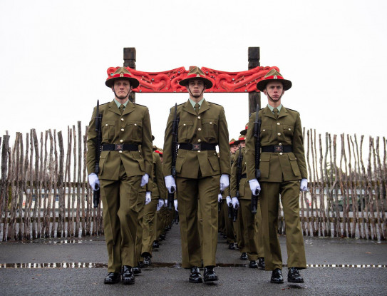 New Zealand Army recruits march in formation through the arch with Māori carvings and onto the parade ground in Waiouru on graduation day