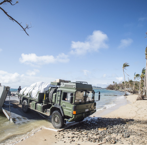 Medium Heavy Operation Vehicle driving off of Landing Craft Mechanism and onto the beach on Fiji. 