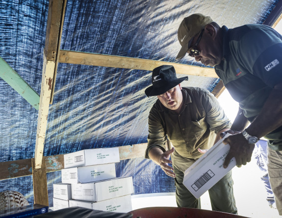 New Zealand Ministry of Foreign Affairs Liaison Officer Mr Nigel Ewels (left) helps stack food aid supplies on Yacata Island after delivery by the Seasprite helicopter.