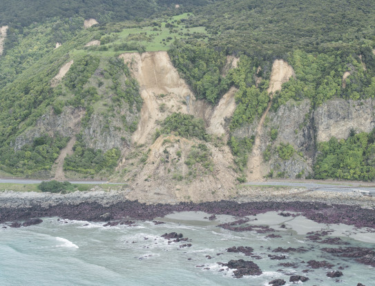 A large landslide blocks State Highway 1 and pushes the railway line into the sea. 