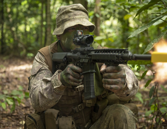 A New Zealand Army Reservist wearing camo paint fires a weapon on Bersama Lima.