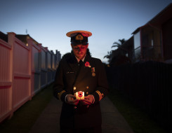 A sailor standing at the end of their driveway holding a candle during stand at dawn 2020