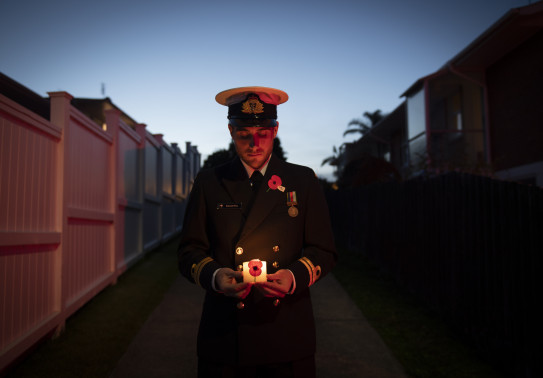A sailor standing at the end of their driveway holding a candle during stand at dawn 2020