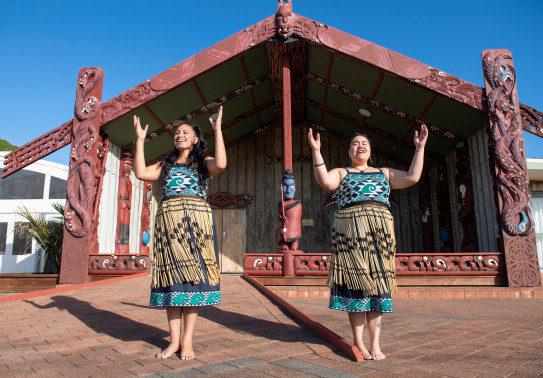 Members of Te Taua Moana Marae performing in front of the marae in cultural dress.