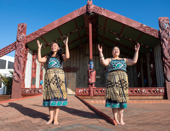 Members of Te Taua Moana Marae performing in front of the marae in cultural dress.
