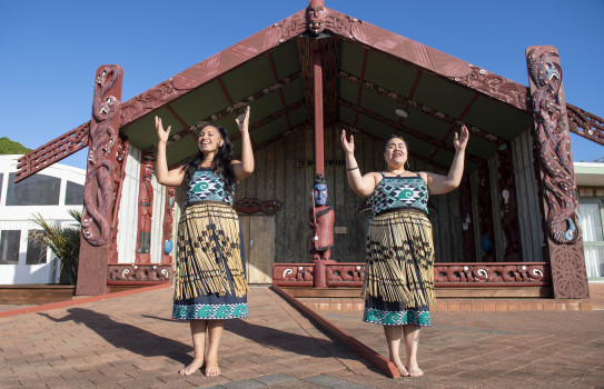 Members of Te Taua Moana Marae performing in front of the marae in cultural dress.