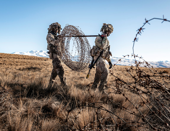 Two soldiers carrying barbed wire through the Tekapo Military Training Area