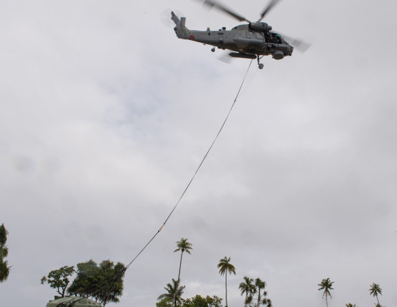 A Seasprite helicopter lifts a water tank from a field in Tokelau 
