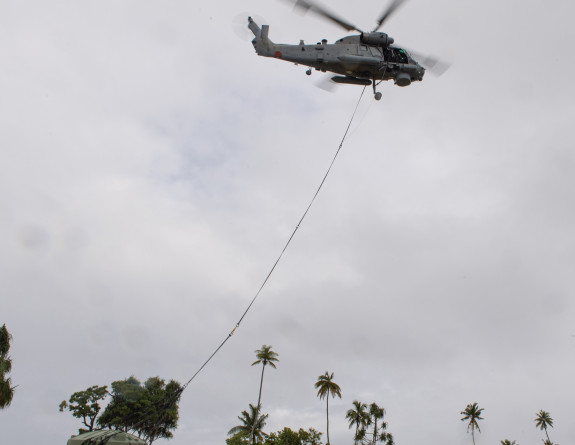 A Seasprite helicopter lifts a water tank from a field in Tokelau